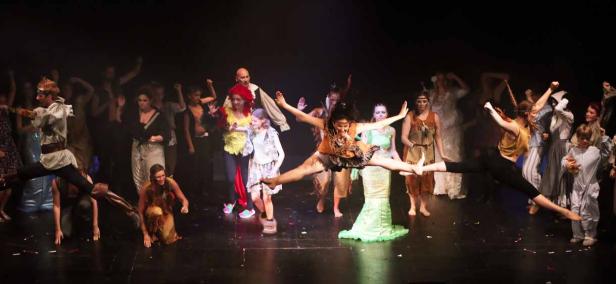 Eine Gruppe von Darstellern in Kostümen auf einer Bühne während einer Aufführung.