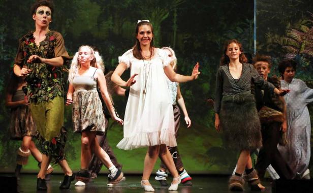 Eine Gruppe von Schauspielern in Kostümen steht auf einer Bühne vor einem Waldhintergrund.