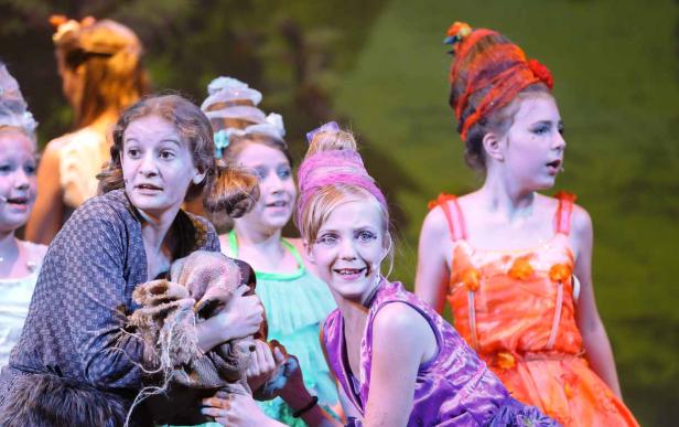 Eine Gruppe junger Schauspielerinnen in bunten Kostümen auf einer Bühne.