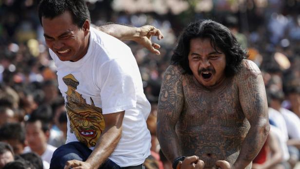 Zwei Männer zeigen während einer Zeremonie angestrengte Gesichtsausdrücke.