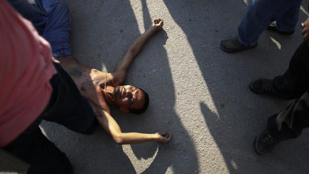 Ein Mann liegt verletzt auf dem Boden, umringt von stehenden Personen.