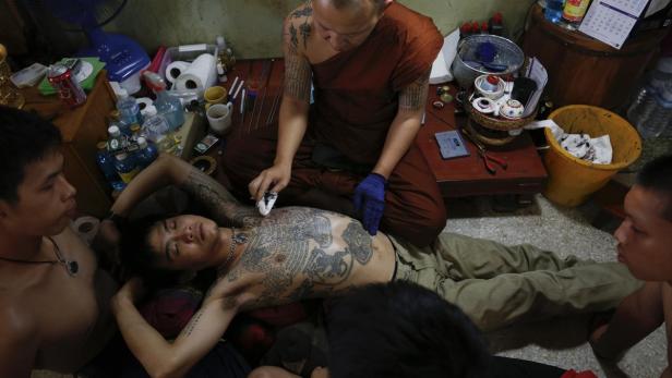 Ein tätowierter Mann erhält von einem buddhistischen Mönch eine weitere Tätowierung.