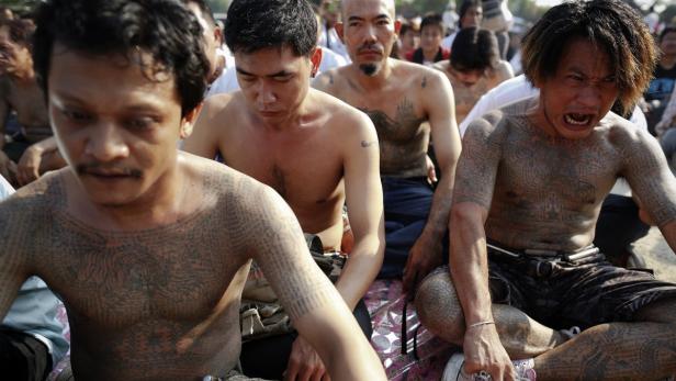 Mehrere Männer mit Tätowierungen sitzen zusammen.