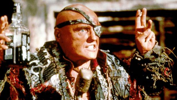 Hugh Keays-Byrne als Immortan Joe in „Mad Max: Fury Road“ mit einer Flasche in der Hand.