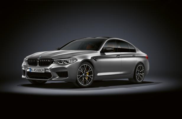 Ein silberner BMW M5 steht vor einem dunklen Hintergrund.