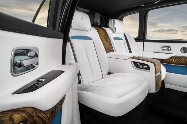 Der Innenraum eines Rolls-Royce mit weißen Ledersitzen und Holzverkleidung.