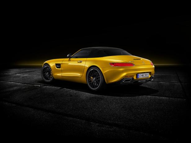 Ein goldgelber Mercedes-AMG GT Roadster von hinten auf dunklem Asphalt.