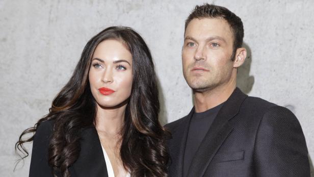 Megan Fox und Brian Austin Green posieren zusammen vor einer grauen Wand.