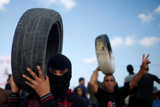 Palestinian demonstrators carry tires during a protest against U.S. embassy move to Jerusalem and ahead of the 70th anniversary of Nakba, at the Israel-Gaza border, east of Gaza City