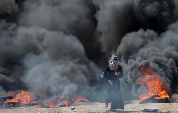 Female Palestinian demonstrator gestures during a protest against U.S. embassy move to Jerusalem and ahead of the 70th anniversary of Nakba, at the Israel-Gaza border, east of Gaza City