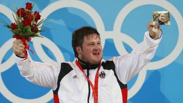 Matthias Steiner feiert seinen Olympiasieg mit einem Blumenstrauß und einem Foto seiner Frau.