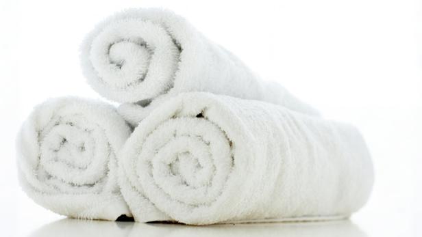 Drei weiße, gerollte Handtücher liegen übereinander.