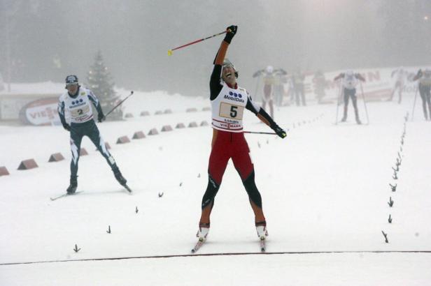 Ein Skilangläufer überquert jubelnd die Ziellinie.