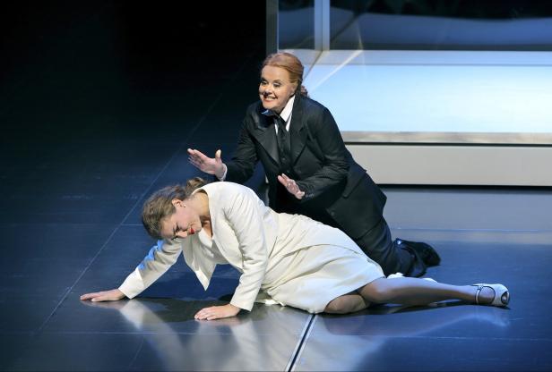 Bayreuther Festspiele 2015 - Lohengrin Eine Frau im Hosenanzug gestikuliert über einer am Boden liegenden Frau in einem weißen Kleid.