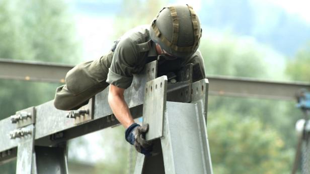 Ein Soldat mit Helm klettert über eine Stahlkonstruktion.
