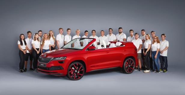 Eine Gruppe junger Leute präsentiert einen roten Škoda Karoq Cabriolet.