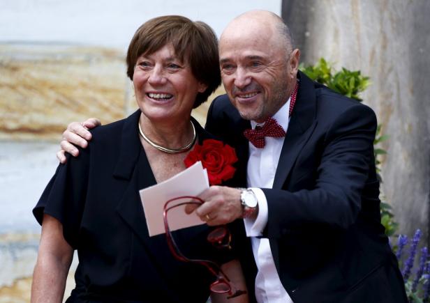 Ein lächelndes Paar, die Frau mit einer roten Rose, der Mann im Anzug mit Fliege.