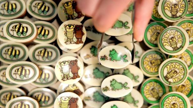 Eine Auswahl von Janosch-Schokoladen mit verschiedenen Motiven wird mit einem Löffel bewegt.