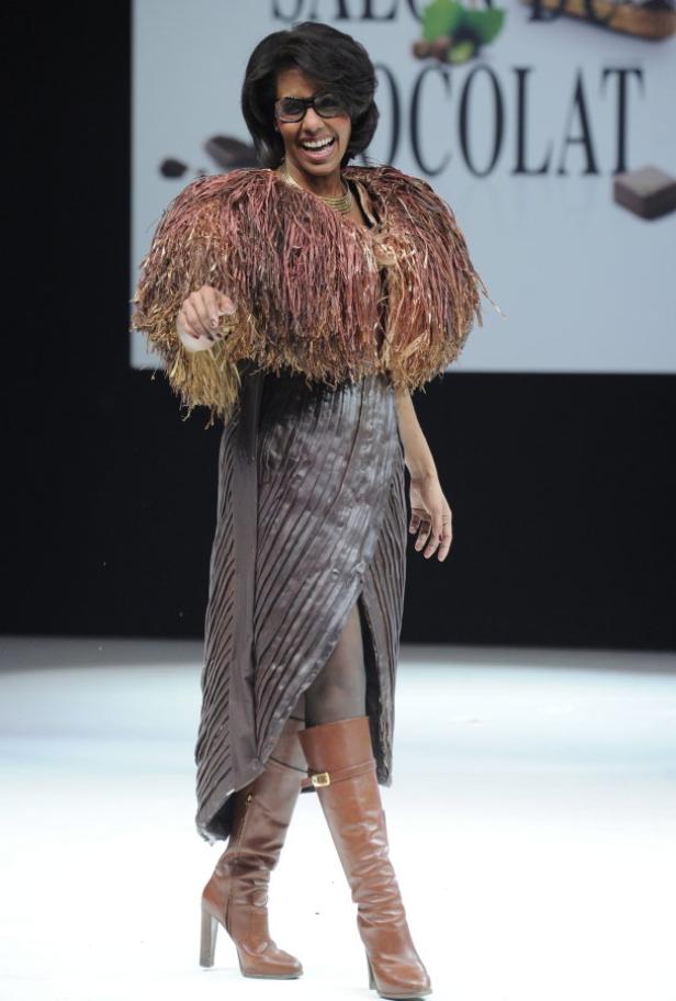 Eine Frau präsentiert ein Kleid und einen Umhang aus Schokolade auf einer Modenschau.