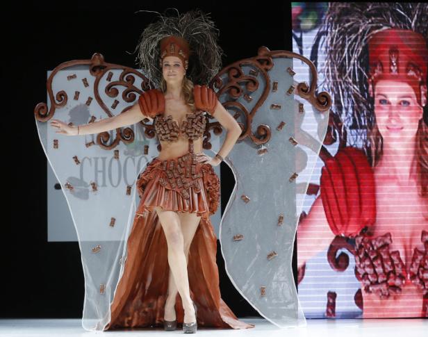 Eine Frau präsentiert ein aufwendiges Kostüm aus Schokolade auf einer Bühne.