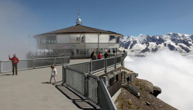 Tourists are seen in front of the revolving restaurant on the peak of the Schilthorn mountain at the Bernese Oberland