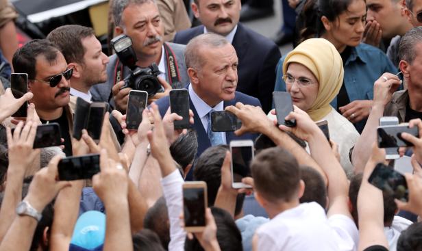 Turkish President Tayyip Erdogan poses for photographs as he leaves a polling station in Istanbul