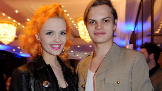 Eine Frau mit orangefarbenem Haar und ein Mann posieren für ein Foto.