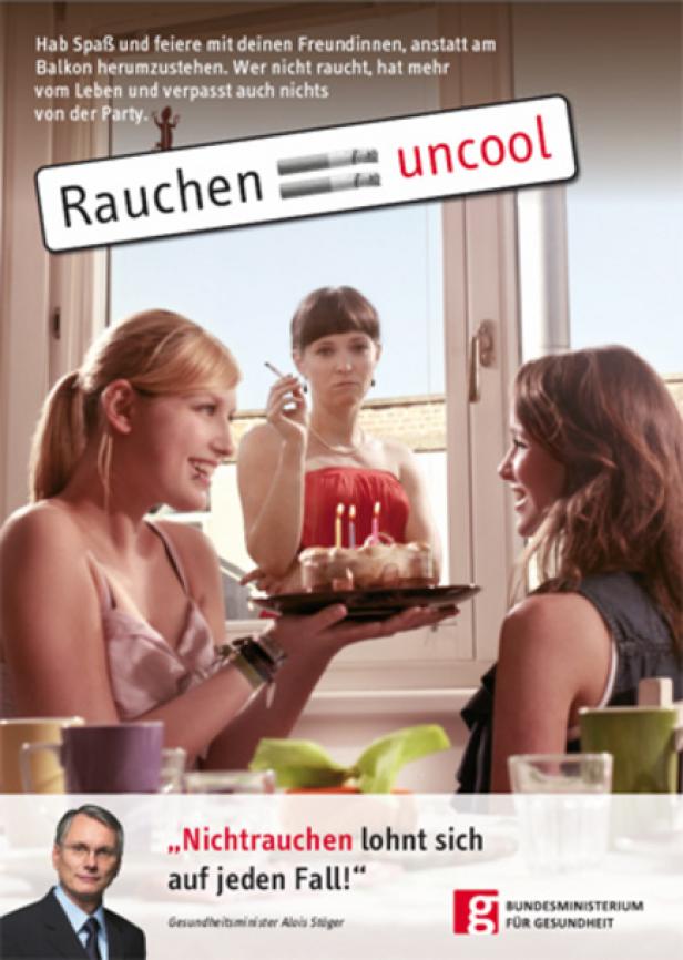 Eine junge Frau hält einen Geburtstagskuchen, während eine andere raucht und unglücklich aussieht. Rauchen ist uncool.