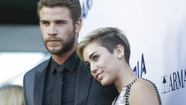 Liam Hemsworth und Miley Cyrus posieren auf einem roten Teppich.