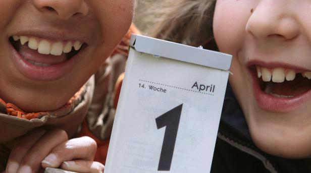 Zwei Kinder halten einen Abreißkalender mit dem Datum 1. April hoch.