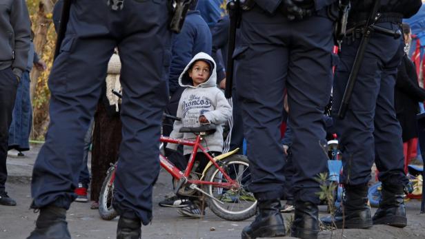 Ein Junge mit Kapuze steht mit seinem Fahrrad zwischen Polizisten.