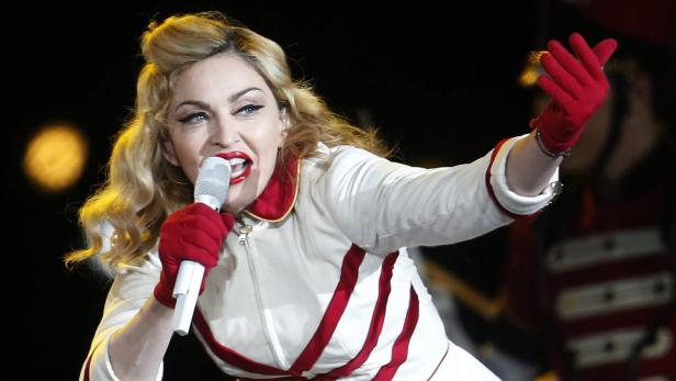 Madonna singt mit rotem Lippenstift und roten Handschuhen in ein Mikrofon.