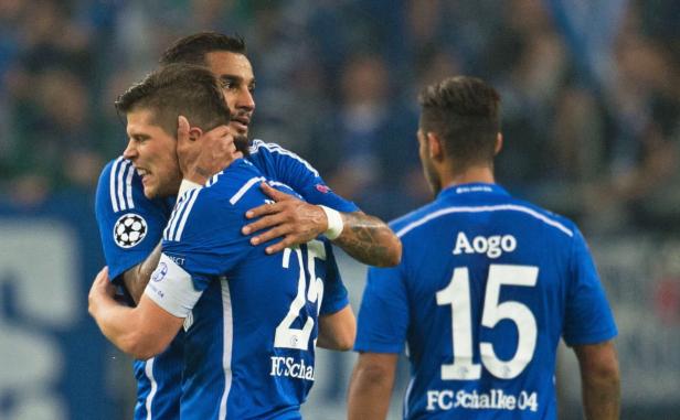 Fußballspieler des FC Schalke 04 umarmen sich auf dem Spielfeld.