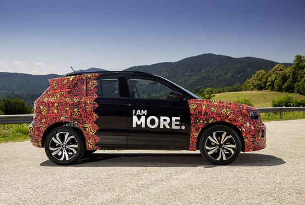 Ein teilweise mit einem Muster beklebter schwarzer VW steht auf einer Straße.