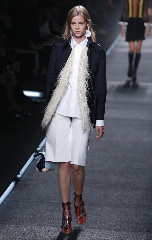 Eine Frau auf dem Laufsteg trägt eine Jacke, Shorts und auffällige Schuhe.