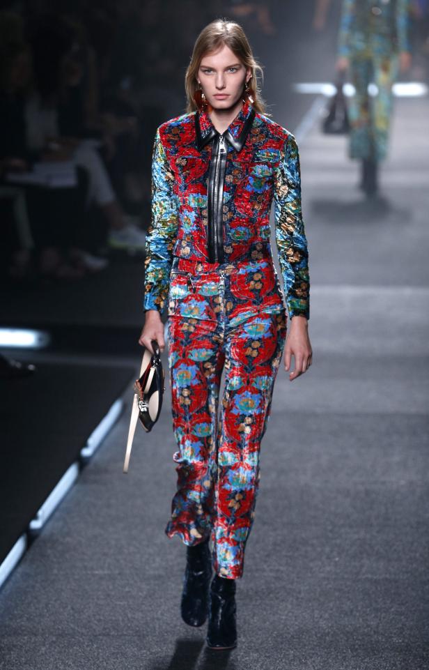 Ein Model präsentiert ein farbenfrohes Hosen- und Jacken-Ensemble auf dem Laufsteg.