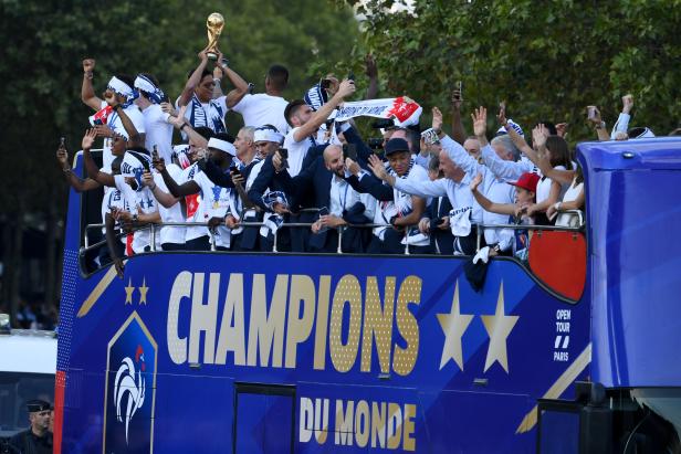 France's defender Raphael Varane holds the trophy as he celebrates with teammates on the roof of a bus while parading down the Champs-Elysee avenue in Paris