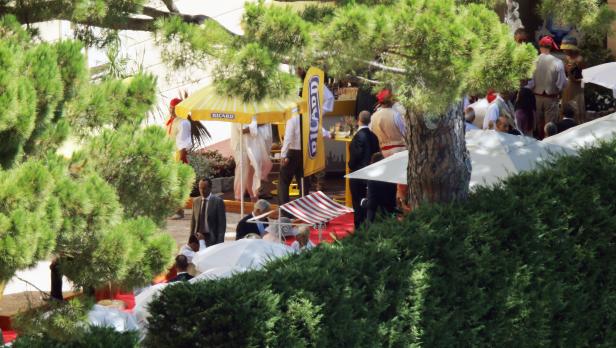 Eine Veranstaltung im Freien mit Menschen unter Sonnenschirmen und einem „Ricard“-Stand.