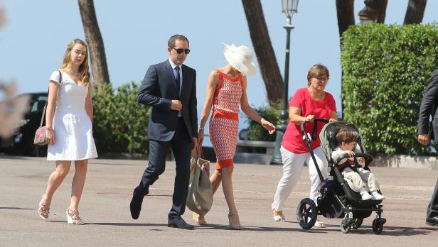 Eine Familie macht einen Spaziergang im Freien, eine Frau schiebt einen Kinderwagen.