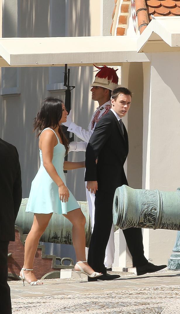 Eine Frau in einem hellblauen Kleid und ein Mann im Anzug gehen an einer Kanone vorbei.