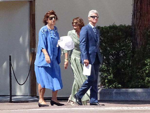 Drei elegant gekleidete Personen gehen auf einer Straße entlang.