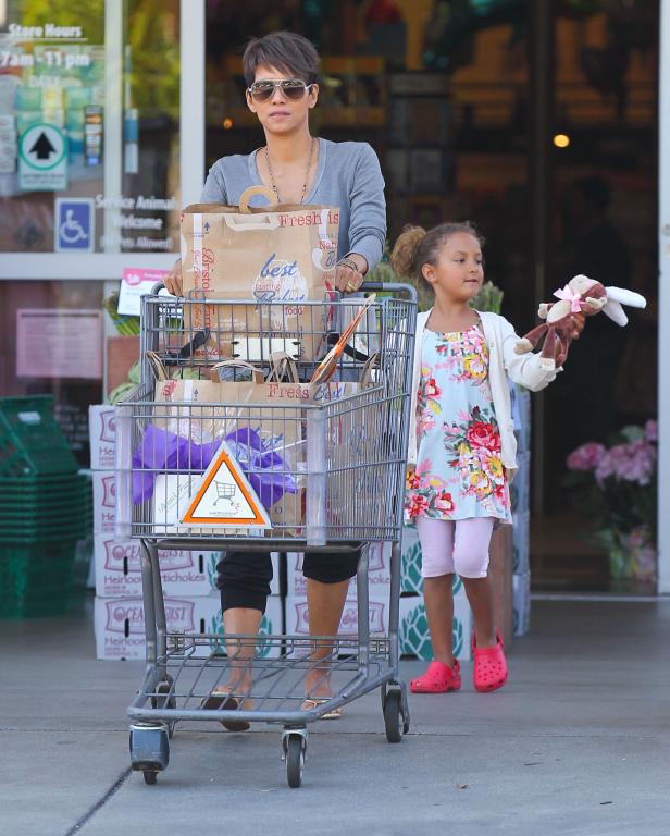 Halle Berry schiebt mit ihrer Tochter einen Einkaufswagen vor einem Supermarkt.