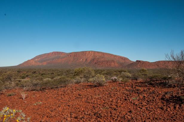 Eine rote Hügellandschaft unter einem klaren, blauen Himmel.