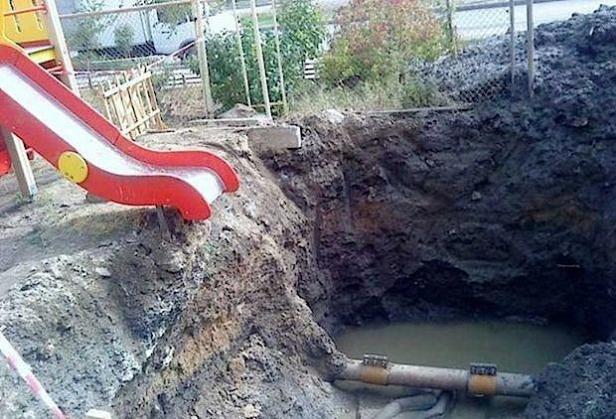 Eine Baugrube neben einer Rutsche auf einem Spielplatz.