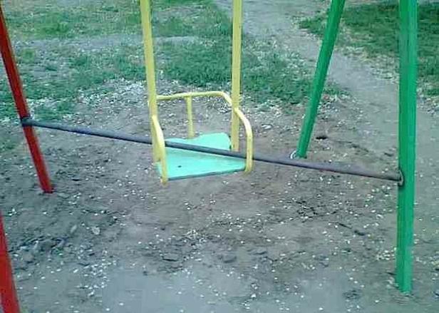 Eine gelb-grüne Schaukel auf einem Spielplatz.