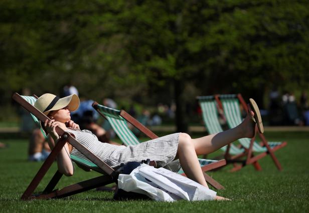 A woman lounges in the sunshine in a deckchair in St James Park, London