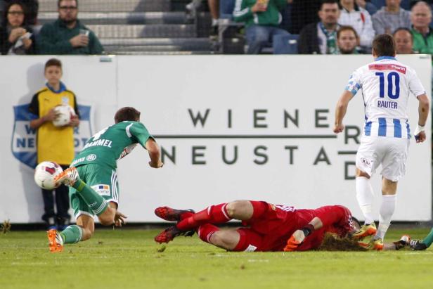Ein Fußballspieler schießt auf das Tor, während der Torwart am Boden liegt.