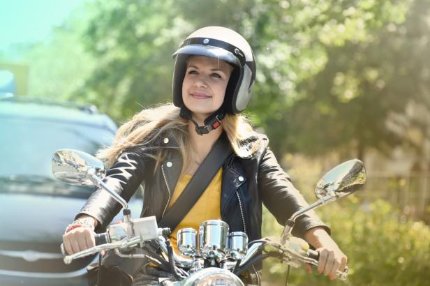 Eine junge Frau mit Helm fährt auf einem Motorroller.