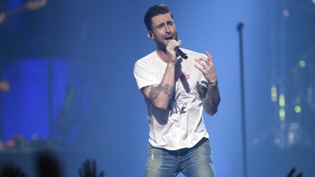 Adam Levine singt während eines Konzerts in ein Mikrofon.