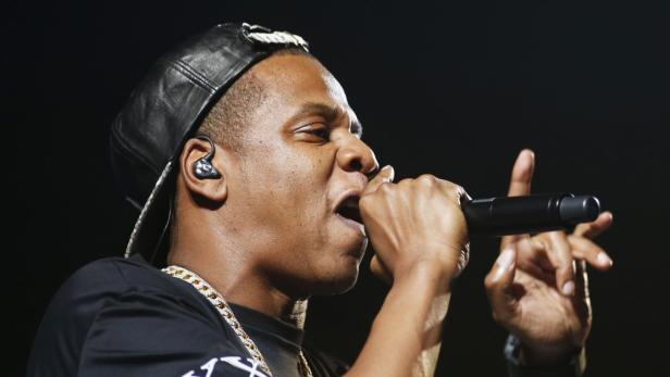 Jay-Z rappt mit einem Mikrofon in der Hand auf einer Bühne.